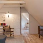 Dachgeschosszimmer mit Holzboden, Sessel, Schrank und Bücherregal.