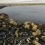 Luftbild eines Dorfes am Wasser mit Häusern und Bäumen.