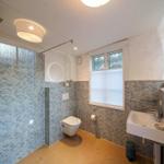 Badezimmer mit Dusche, Waschbecken und Toilette. Wände mit Wellenmustertiles.