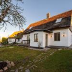 Wohnhaus mit Strohdach, weißer Fassade und Gartenweg. Hausnummer 33.