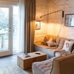 Ein Wohnbereich mit Sofa, Tisch und Terrassentür. Weiße Ziegelwand und Bilder.