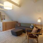 Wohnraum mit Sofa, Sessel und Holzboden unter schrägen Dachschrägen.