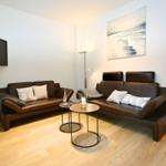 Wohnzimmer mit zwei Ledersofas, Fernseher und Wandbild.