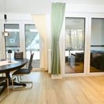 Essbereich mit Tisch und Stühlen, Durchgang zu Terrasse mit Sitzgruppe und Blick auf Wald.