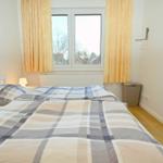 Schlafzimmer mit Doppelbett, Fenster und Gardinen