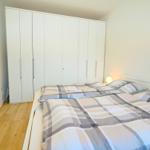 Schlafzimmer mit Doppelbett, weißem Schrank und Holzboden.