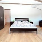 Schlafzimmer mit Doppelbett, Kleiderschrank und Sitzgelegenheit unter Dachschrägen.