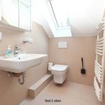 Badezimmer mit Waschbecken, Toilette und Dusche unter Dachschrägen.