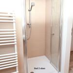 Dusche mit Glaswand und Heizkörper an der Wand