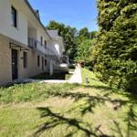 Modernes Haus mit Balkon, Gartenweg und grüner Umgebung.