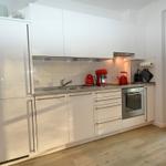 Moderne Küche mit weißen Schränken, roten Küchenutensilien und integriertem Ofen.