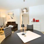 Essbereich mit runder Tisch und Stühlen. Wohnbereich mit Sofa und Wandbild.