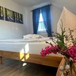 Schlafzimmer mit Holzbett, blauen Vorhängen und Wandbildern