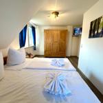 Schlafzimmer mit Doppelbett, Holzschrank und Wandbildern