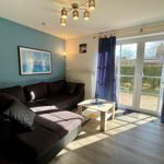 Wohnzimmer mit Sofa, Tisch und Glastür zum Garten.