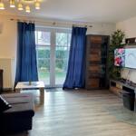 Wohnzimmer mit Sofa, TV und Fenster zur Außenterrasse.