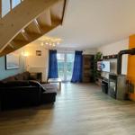 Wohnzimmer mit Sofa, TV und Kaminofen. Holztreppe und Terrassentür.