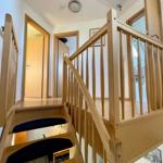Holztreppe mit schwarzen Stufen und Geländer führt zur oberen Etage.