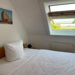 Schlafzimmer mit Dachfenster und Bett. Wandbild zeigt ein Boot.