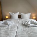 Zwei Betten mit weißen Laken und Handtüchern. Beide Nachttische mit Lampen.