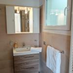 Badezimmer mit Waschbecken, Spiegelschrank, Fenster und Handtuchhalter.