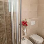 Badezimmer mit Dusche, Waschbecken und Toilette. Blume als Dekoration.