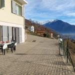 Terrasse mit Tisch und Stühlen, Blick auf Berge und See.