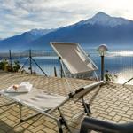 Liegestuhl auf Terrasse mit Blick auf See und Berge.