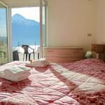 Schlafzimmer mit Blick auf Berg und See. Bett mit Handtüchern, Schrank und Nachttisch.