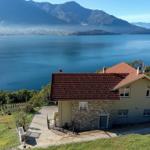 Haus mit Blick auf See und Berge. Terrasse, Garten und Zufahrt sichtbar.