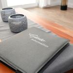 Gästeinformation liegt auf einem Holztisch mit grauer Tischdecke und zwei dekorativen Schalen.