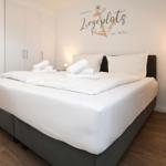 Schlafzimmer mit Doppelbett, weißen Laken und Wanddekoration mit Anker.