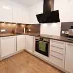 Moderne Küche mit weißen Schränken, dunkler Arbeitsplatte und integriertem Herd.