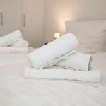 Das Bett ist mit weißen Laken bezogen und mit gefalteten Handtüchern dekoriert.