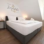 Schlafzimmer mit Bett, Wanddekoration und Fenster mit Jalousie.