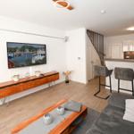 Wohnbereich mit TV, Sofa und Küchenbereich mit Barhocker.