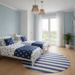 Zwei Betten mit Ankern-Muster, blauer Teppich, weiße Wände und Balkon mit Blick.