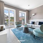 Wohnzimmer mit Sofa, Sesseln und Blick auf Balkon.