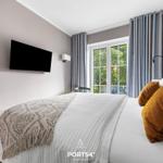 Schlafzimmer mit Bett, TV und Fenster zur Terrasse