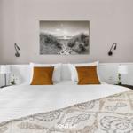 Schlafzimmer mit Bett, Wandbild und Nachttischen.