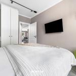 Schlafzimmer mit Bett, Kleiderschrank und Fernseher an der Wand.