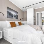 Schlafzimmer mit weißem Bett, Wandbild und Schwebetüren.