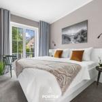 Schlafzimmer mit Bett, Fenster, TV und Nachttisch.