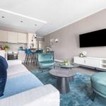 Wohnbereich mit Sofa, Sessel und Küchenbereich. Fernseher an der Wand.