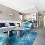 Wohnbereich mit Sofa, Sessel und Küchenbereich. Blauer Teppich und moderne Einrichtung.