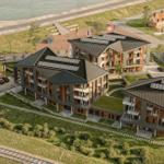 Modernes Mehrfamilienhaus mit Solaranlagen und grünen Flächen am Wasser.