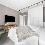 Schlafzimmer mit Bett, Kleiderschrank, Fernseher und Pflanzen.