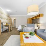 Wohnbereich mit Sofa, Sessel und Bett. Holzmöbel und dekorative Wandgestaltung.