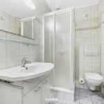 Badezimmer mit Dusche, Waschbecken und Toilette. Fliesenwand mit Muschel-Motiv.