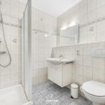 Badezimmer mit Dusche, Waschbecken und WC. Fliesen mit Muschel-Motiv.